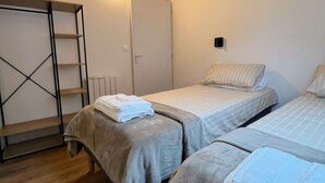 Ett sovrum med två sängar, ett träpanelat tak, en garderob och en väggmonterad lampa.
