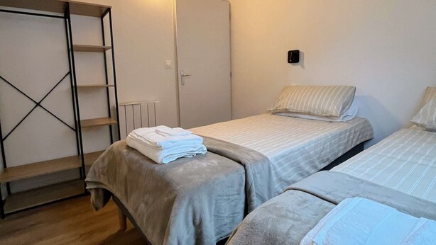 Et soveværelse med to senge, trælofter, et skab og en lampe på væggen.