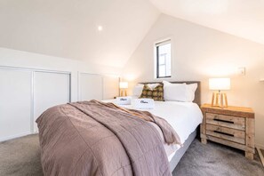 A bedroom with a bed, bedside tables, a window, and a ceiling light. - Cozy Central Loft | Walk to CBD & Stadium (Christchurch)