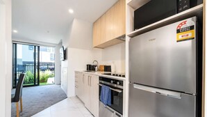 A modern kitchen with stainless steel appliances, a dining area with a chair, and a view of the outside. - Cozy Central Loft | Walk to CBD & Stadium (Christchurch)