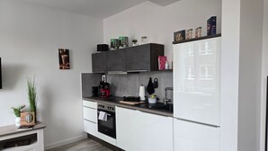 Een moderne keuken met witte kastjes, een zwarte kookplaat en een rode koffiezetapparaat.