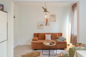 Een moderne woonkamer met een bruine bank, een klein rond tafeltje en een hangende vogelsculptuur.