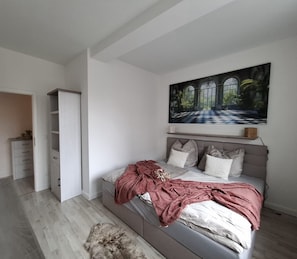 Una camera da letto con un letto, un armadio, un quadro e vista sul verde.