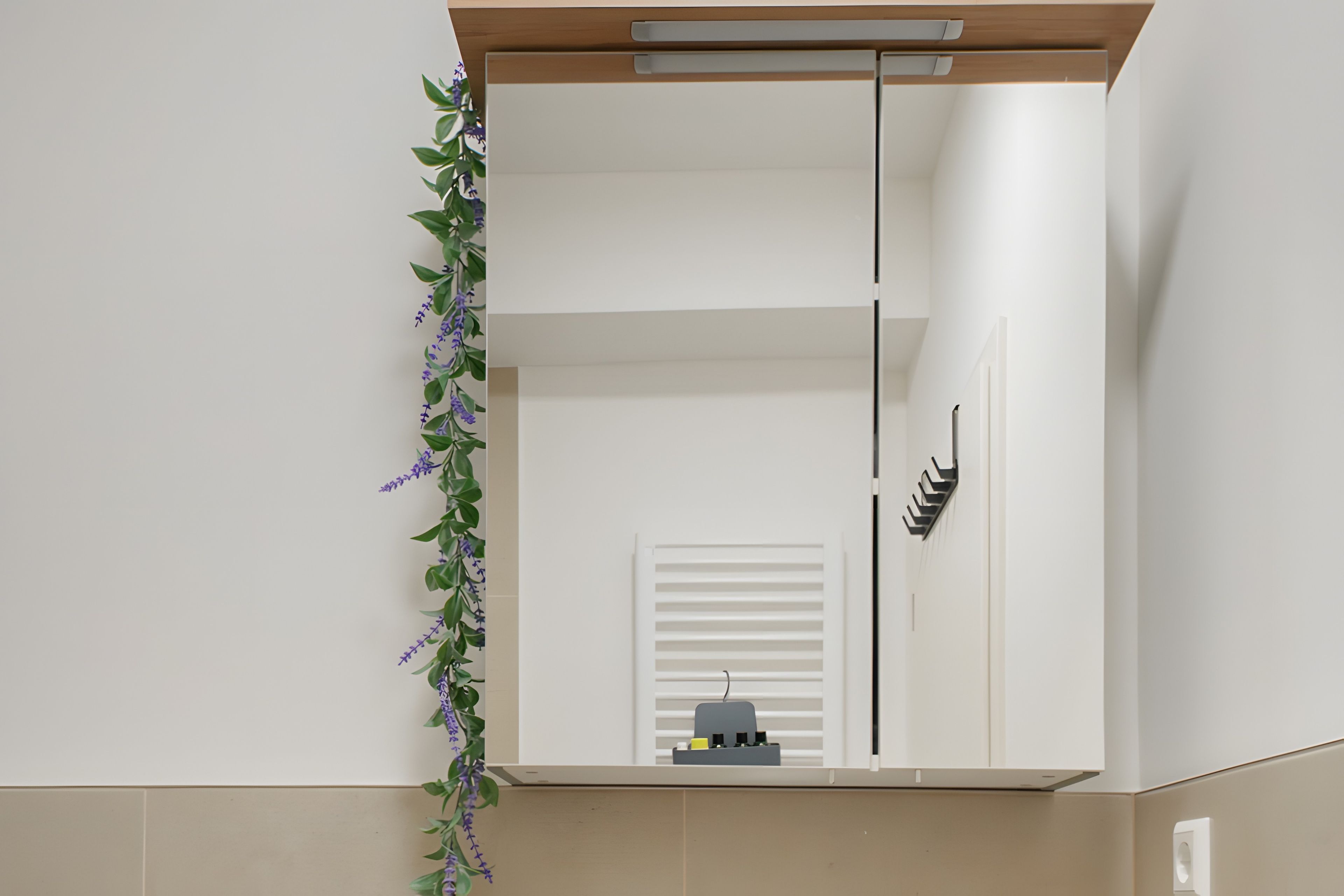 Een badkamer met een grote spiegel, een handdoekhouder en een plant.
