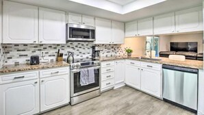 A modern kitchen with white cabinetry, a microwave, an oven, and a dishwasher. - Justin Richardson Home w/ Outdoor Oasis & Movie Room (Richardson)