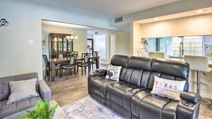A modern living room with a leather sofa, a dining area with a table and chairs, and a kitchen area with bar stools. - Justin Richardson Home w/ Outdoor Oasis & Movie Room (Richardson)