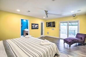 Un dormitorio con cama, una silla, televisión y balcón.
