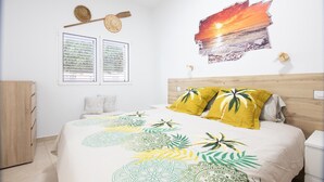 A bedroom with a bed, a window, a wall clock, and a sunset painting. - Vacation Home 'Holiday Esquinita' with Wi-Fi and Air Conditioning (San Bartolomé de Tirajana)