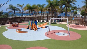 A playground with various play structures, a wooden fence, and palm trees. - Vacation Home 'Holiday Esquinita' with Wi-Fi and Air Conditioning (San Bartolomé de Tirajana)
