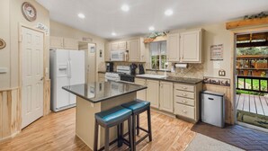 A kitchen with a central island, wooden cabinets, a refrigerator, a microwave, and a sink.