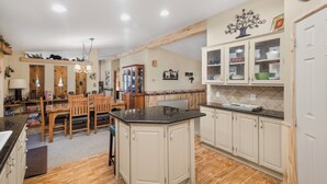 A spacious kitchen with wooden cabinets, a central island, and a dining area with wooden chairs.