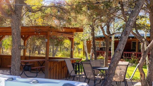 An outdoor patio area with wooden tables and chairs, a hot tub, and a covered seating area.