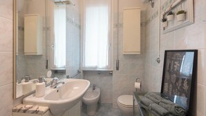 Un bany amb un envàs gran, bidet, vàter i un jardí d'herbes en marc a la paret.