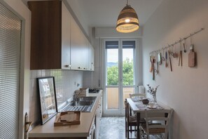 Una cocina moderna con un ventanal grande, un comedor con mesa y sillas, y una variedad de utensilios de cocina colgados en la pared.
