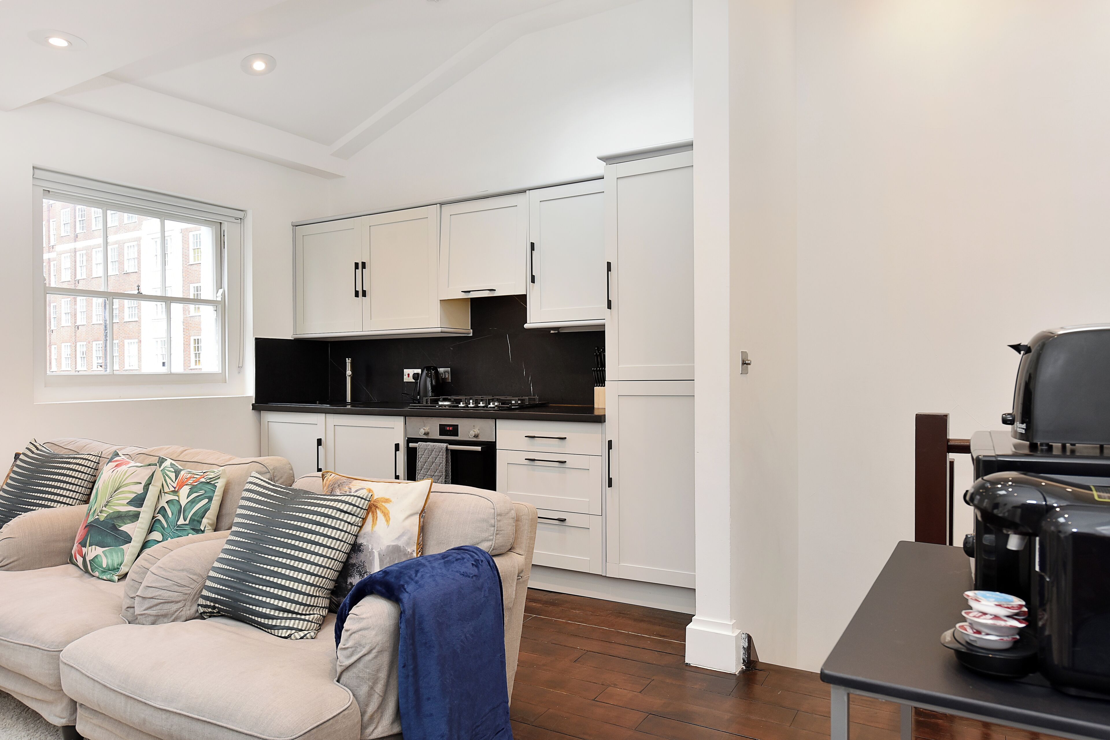 A modern kitchen with white cabinets, a black countertop, and a coffee machine.