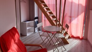 A room with a wooden staircase, a white table, and a red chair.