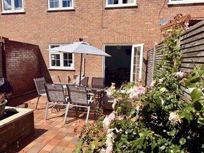 Eine Terrasse mit Gartenmöbeln, einem Tisch und Stühlen.