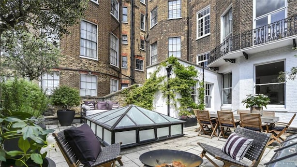 A courtyard with outdoor seating, a glass greenhouse, and a fire pit. - Harley Street Elegance With Private Garden (London)