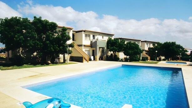 Una piscina con un juguete inflable azul, rodeada de edificios y árboles.