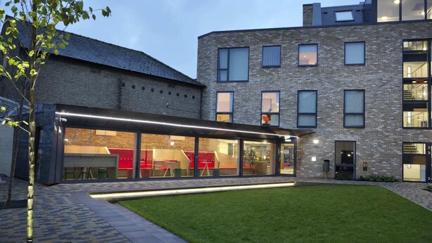 A modern building with a brick facade, large windows, and a well-maintained lawn. - For Students Only - Studios in Cambridge (Cambridge)