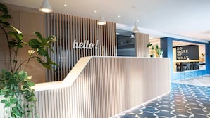 A reception area with a 'hello!' sign, a modern design with vertical wooden slats, and a geometric patterned floor. - For Students Only - Studios in Cambridge (Cambridge)