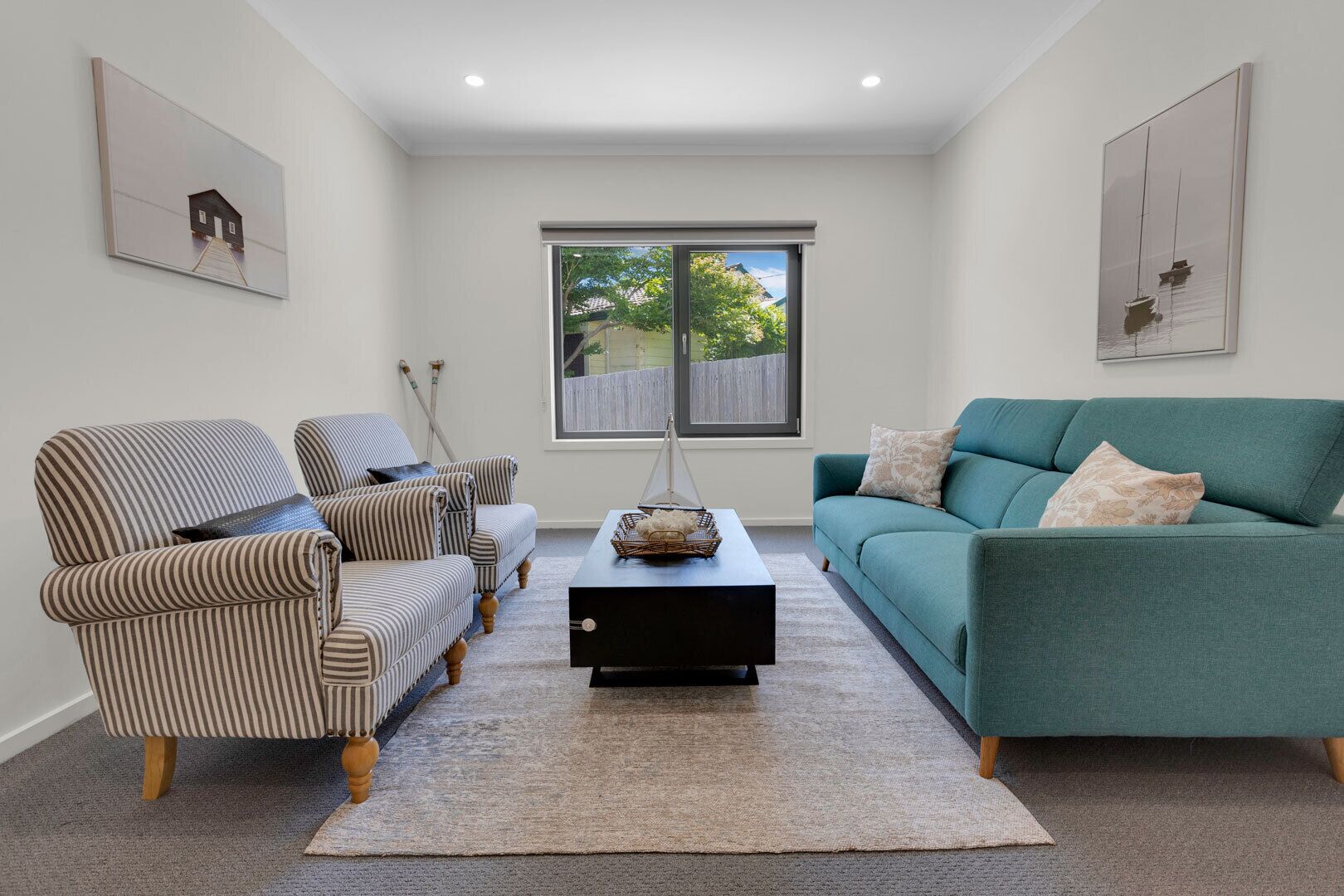 A living room with striped armchairs, a teal sofa, and a coffee table.