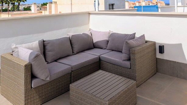 A rooftop terrace with a sectional sofa and a small table, a large umbrella, and a view of the cityscape. - Modern Apartment "R-60-B" in Torrevieja (Torrevieja)