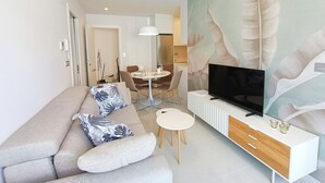 A modern living room with a sofa, TV, and dining area. - Modern Apartment "R-60-B" in Torrevieja (Torrevieja)
