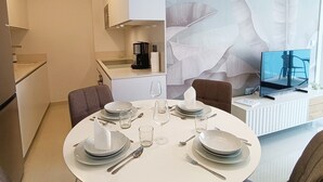 A modern dining area with a round table set for four, a coffee machine, and a television on a white console. - Modern Apartment "R-60-B" in Torrevieja (Torrevieja)