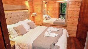 A bedroom with a large bed, a mirror, wooden walls, and a nightstand. - Papalo Resort Hotel (Altos)