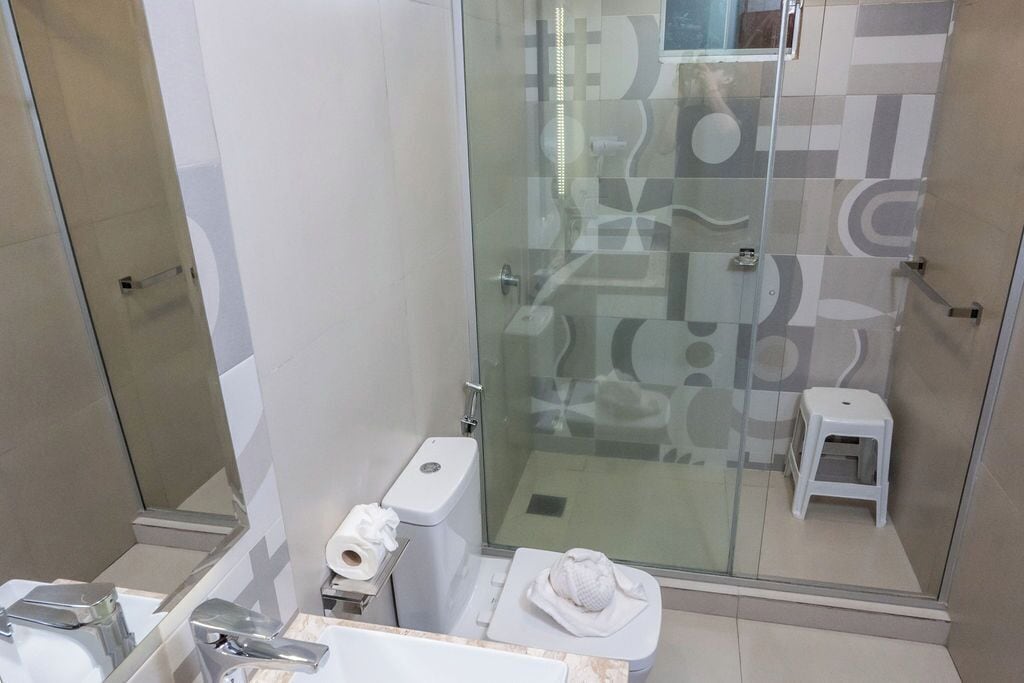 Un baño moderno con ducha de vidrio, inodoro y lavamanos.