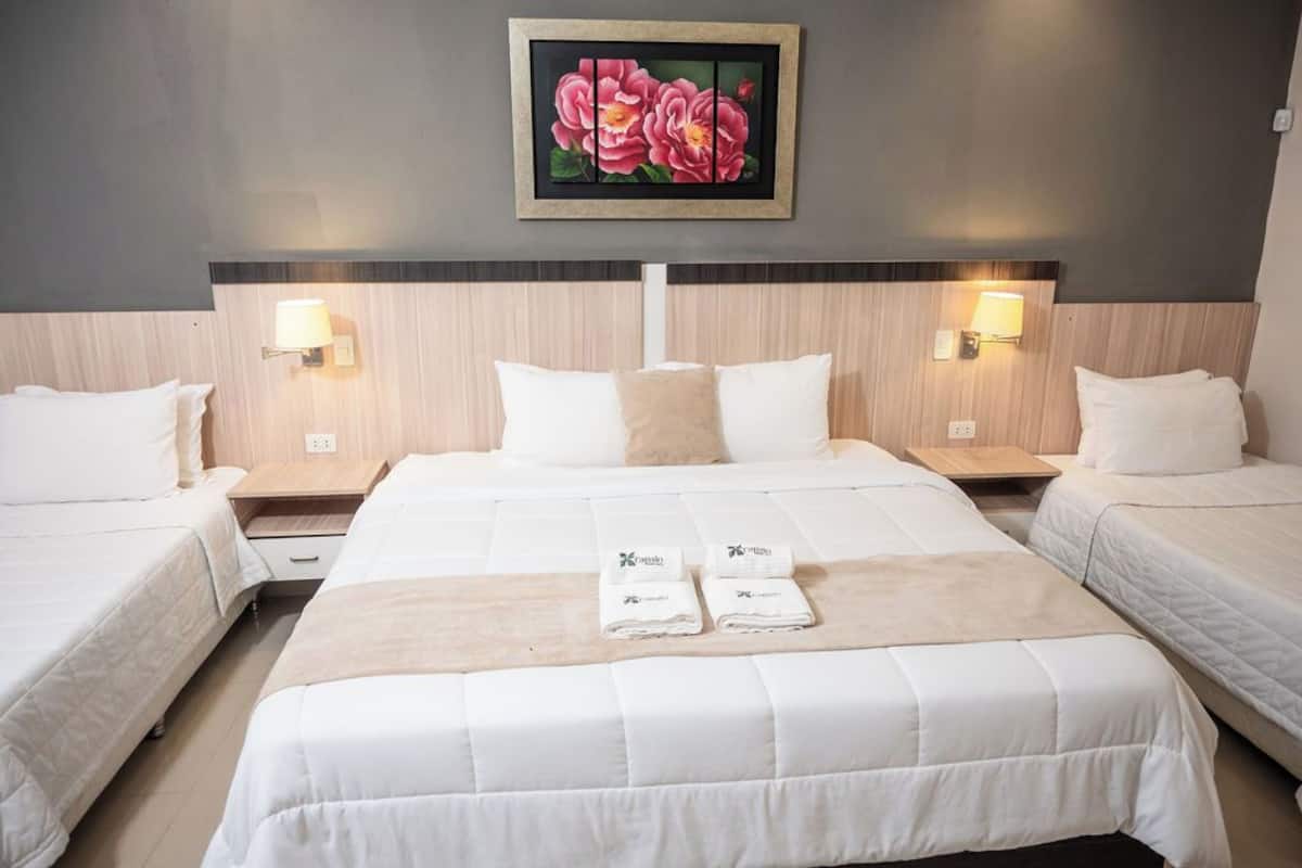 A hotel room with a large bed, two bedside tables, and a painting of flowers on the wall.