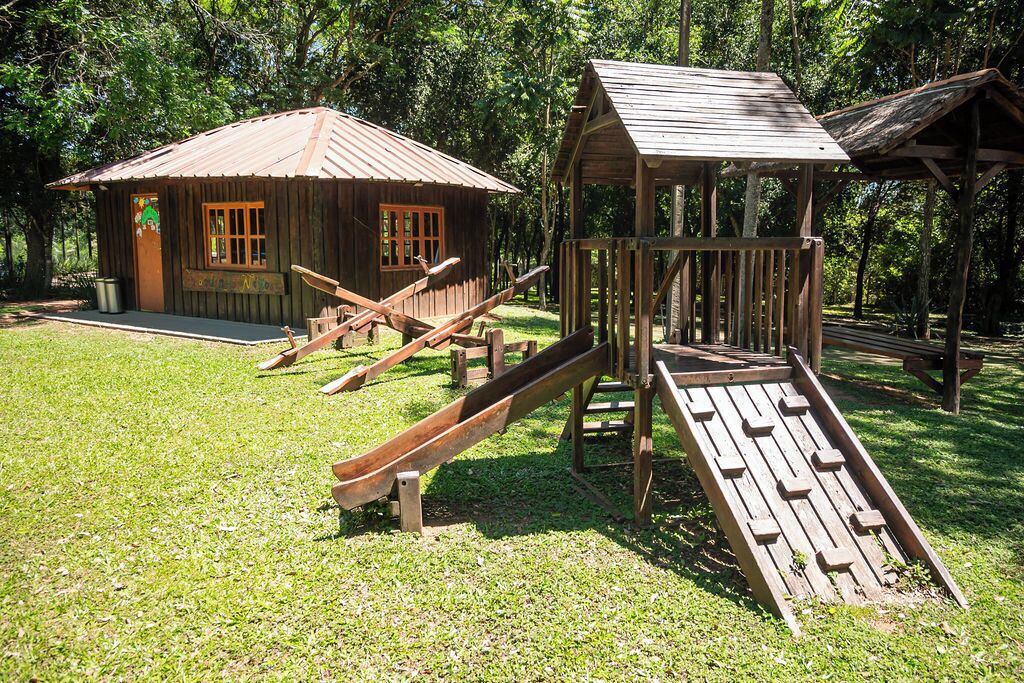 A rustic wooden play structure with a slide and a small cabin-like building.