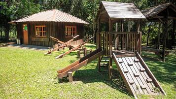A rustic wooden play structure with a slide and a small cabin-like building.