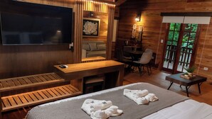 A cozy room with a bed, a desk, a TV, and a seating area. - Papalo Resort Hotel (Altos)
