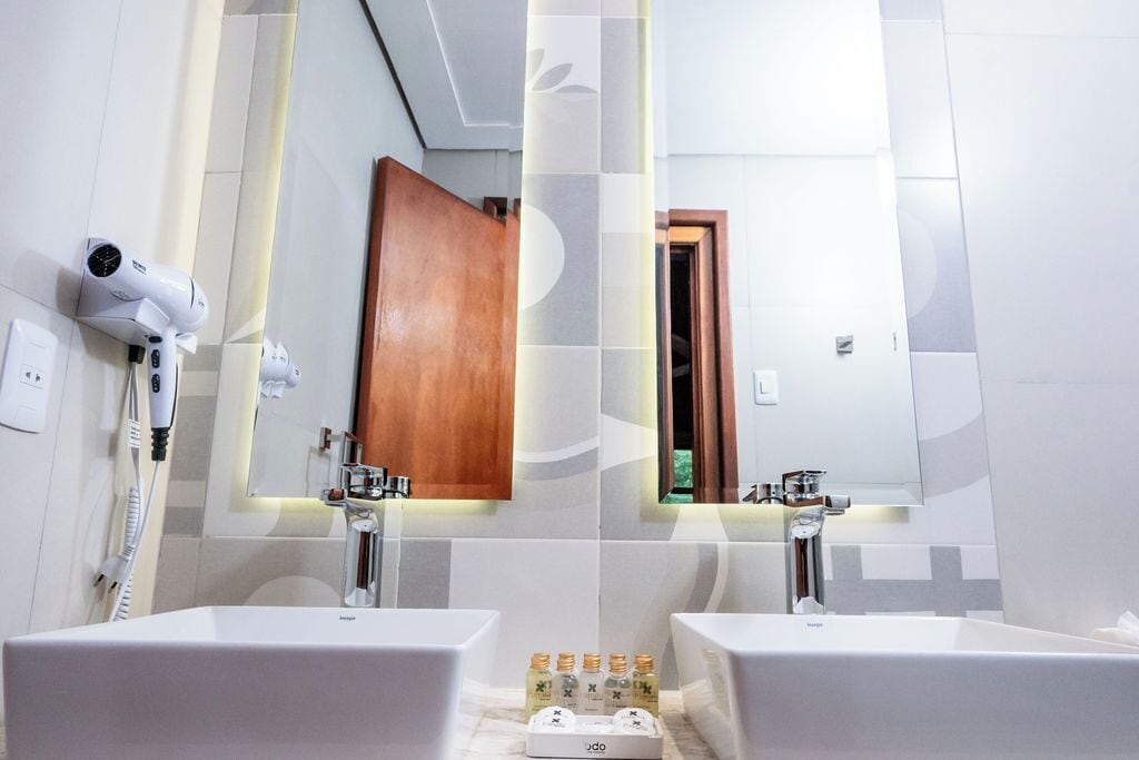 Un baño moderno con dos lavamanos, un secador de pelo y un espejo.