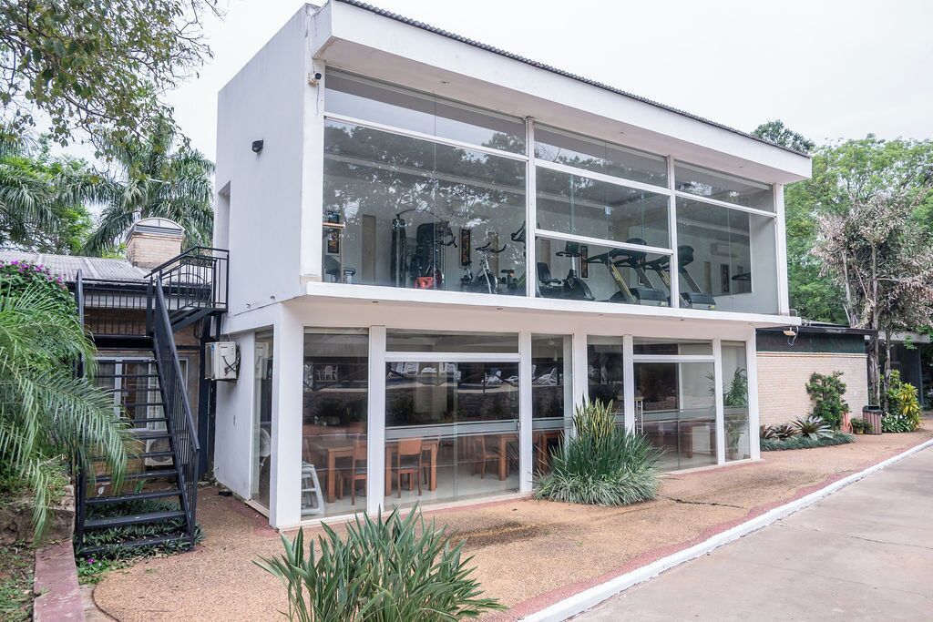 Un edificio moderno de dos pisos con amplios ventanales, una escalera y un área de estar al aire libre.