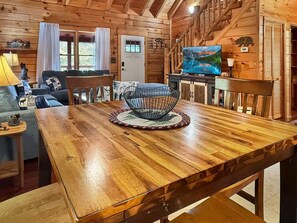 Een houten interieur met een eettafel, stoelen, een bank en een televisie.