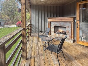 Eine Holzterrasse mit Kamin und zwei Stühlen.
