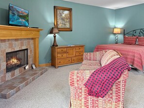 Ein Schlafzimmer mit Kamin, einem Bett, einem Schminktisch und einem Bild an der Wand.