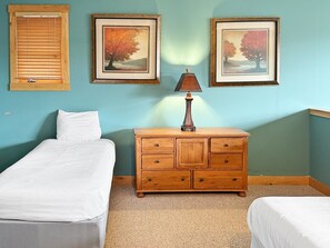 Ein Schlafzimmer mit zwei Betten, einem Holzschrank und zwei gerahmten Bildern an der Wand.