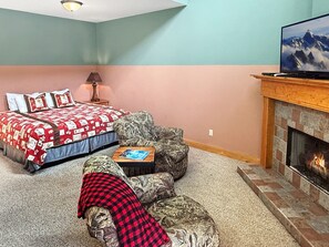 Ein Schlafzimmer mit einem Bett, einem Fernseher, einem Kamin und Teppichboden.