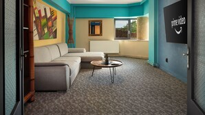 A modern living room with teal walls, a sectional sofa, a coffee table, and a large painting. - Lapusneanu Central Apartments (Iași)
