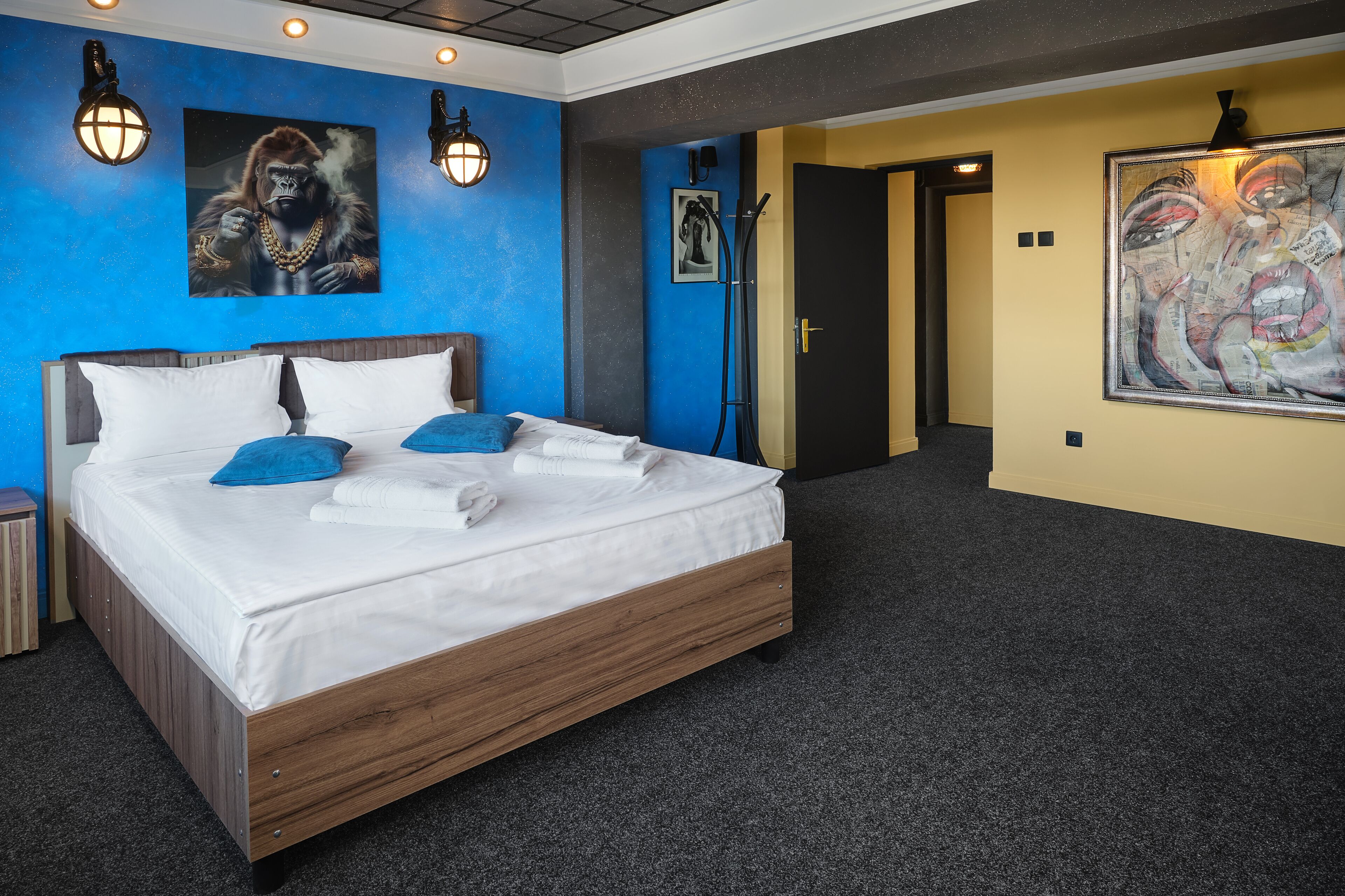 Une chambre d’hôtel moderne avec un grand lit, des murs d’un bleu vif et des œuvres d’art.