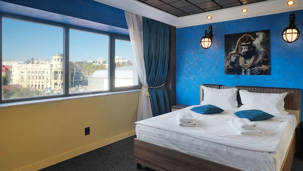 A hotel room with a large bed, a view of a cityscape, and two wall-mounted lights. - Lapusneanu Central Apartments (Iași)