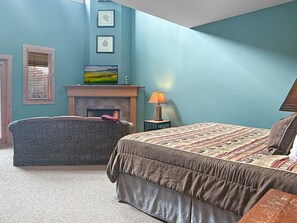 Ein Schlafzimmer mit einem Bett, einem Sofa, einem Kamin und einer Wand mit gerahmten Bildern.