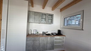 Cocina compacta con armarios grises, encimera de madera y ventana con persianas.