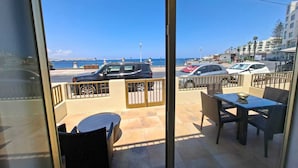 A balcony with a view of the sea, a car parked outside, and a table with chairs. - Steps Away from the Sea- Beach Front Free Parking! (San Pawl il-Baħar)