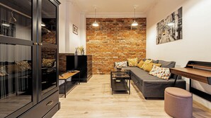 A modern living room with a brick wall, a sofa, a coffee table, and a cabinet. - RentPlanet - Wyspiańskiego (Poznań)