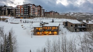 Un hôtel moderne à plusieurs étages, offrant une vue sur un paysage enneigé, avec un bâtiment imposant doté de grandes fenêtres et d’une entrée bien éclairée.